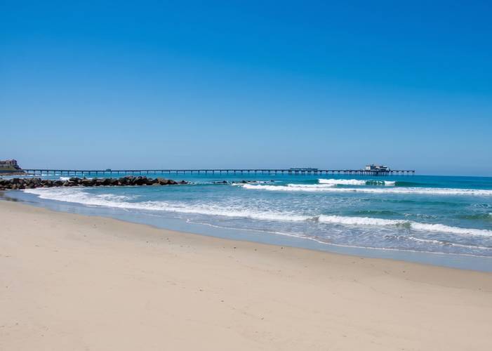 Avalanche surf break in Ocean Beach, San Diego — jetty boulders at the waterline with the pier across the distance.