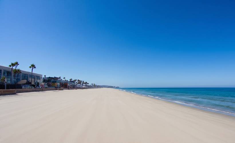 Belmont Park surf break in Mission Beach, San Diego — the Belmont Park building and its palms above open sand.