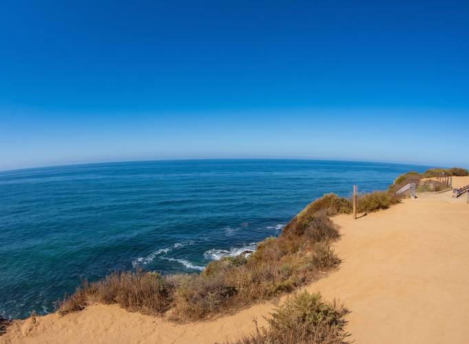 Garbage surf break in Sunset Cliffs, San Diego — the bluff trail, scrub and railing above the water.