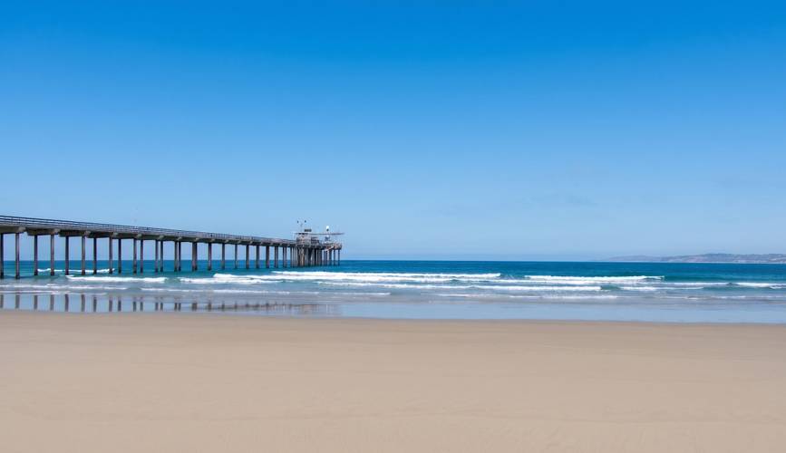 North Scripps surf break in La Jolla, San Diego — Scripps Pier from the sand, pilings running to the instrument head.