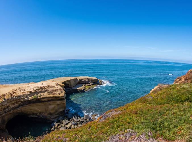 Osprey surf break in Sunset Cliffs, San Diego — the sandstone point and its sea cave above an iceplant slope.